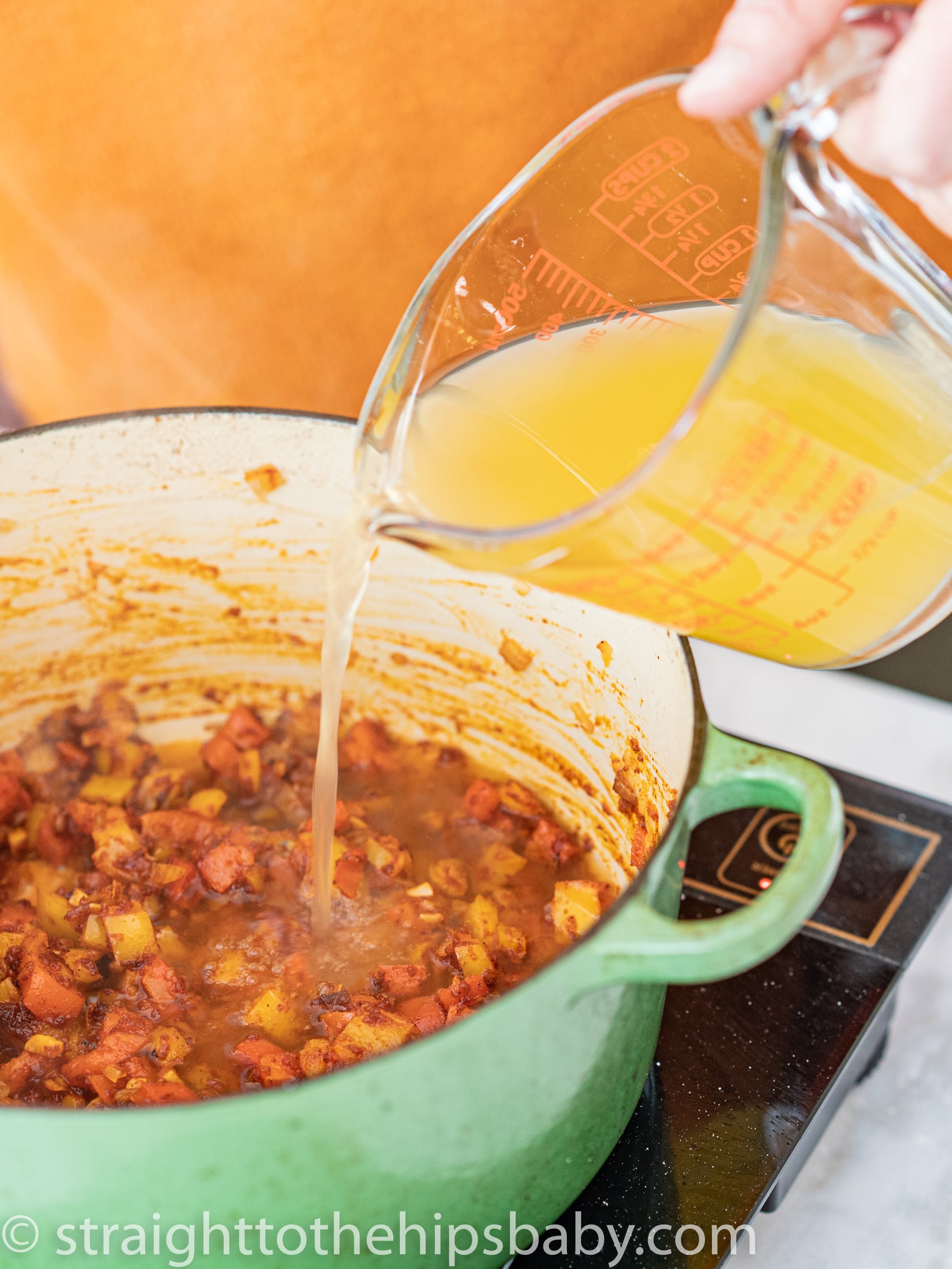 Pouring chicken stock into paprikash sauce roux