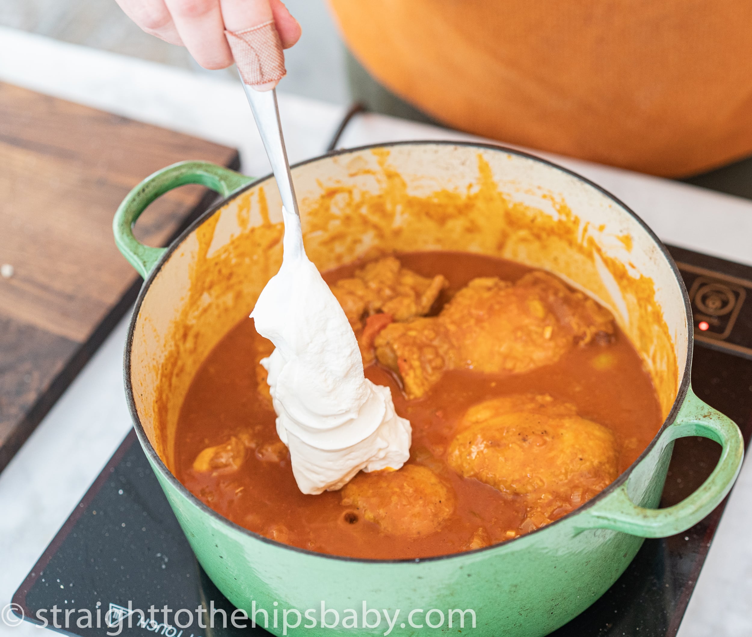Stirring sour cream into chicken paprikash for a rich creamy sauce]