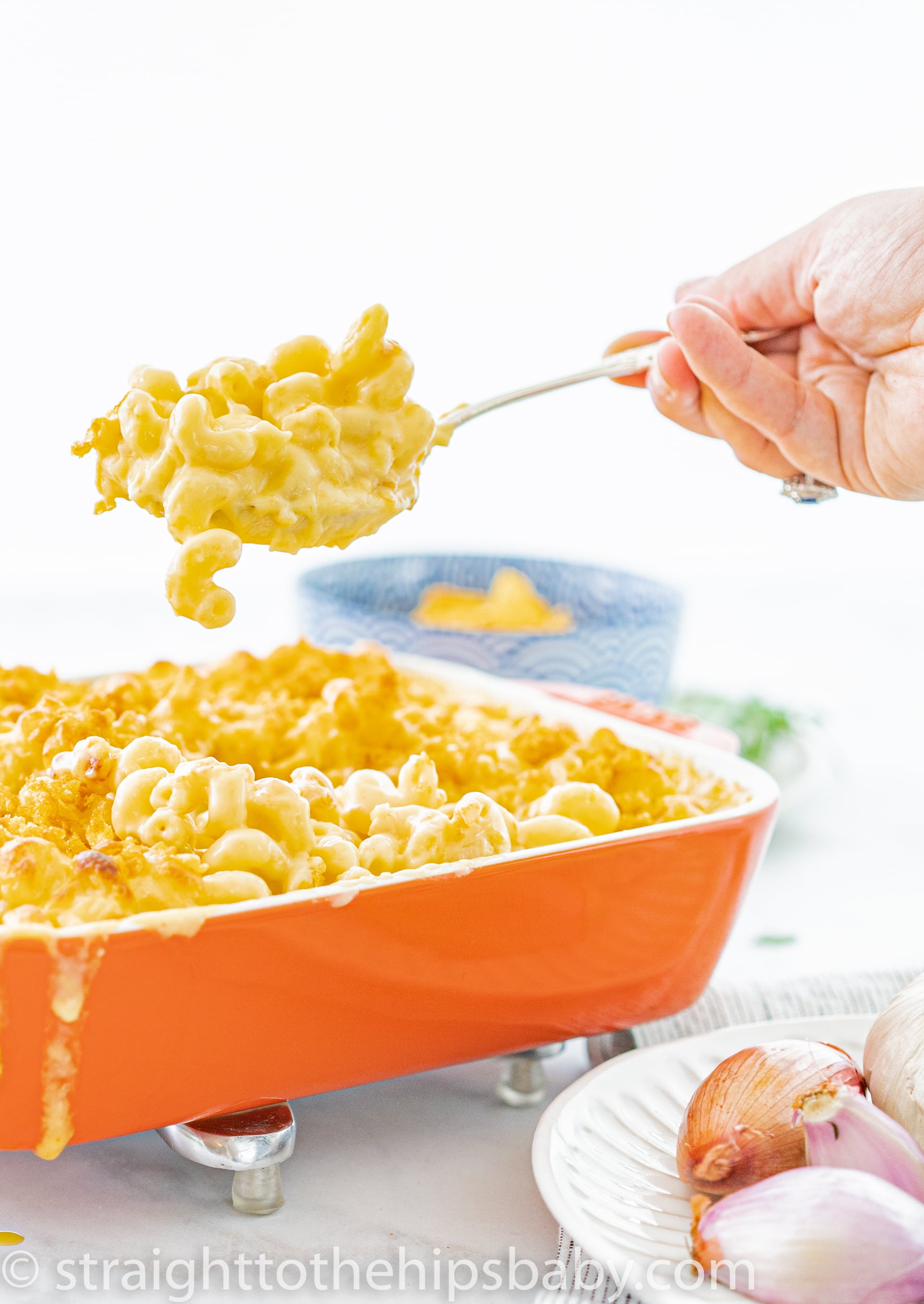 Close-up scoop of baked gruyere mac and cheese showing creamy cheese pull