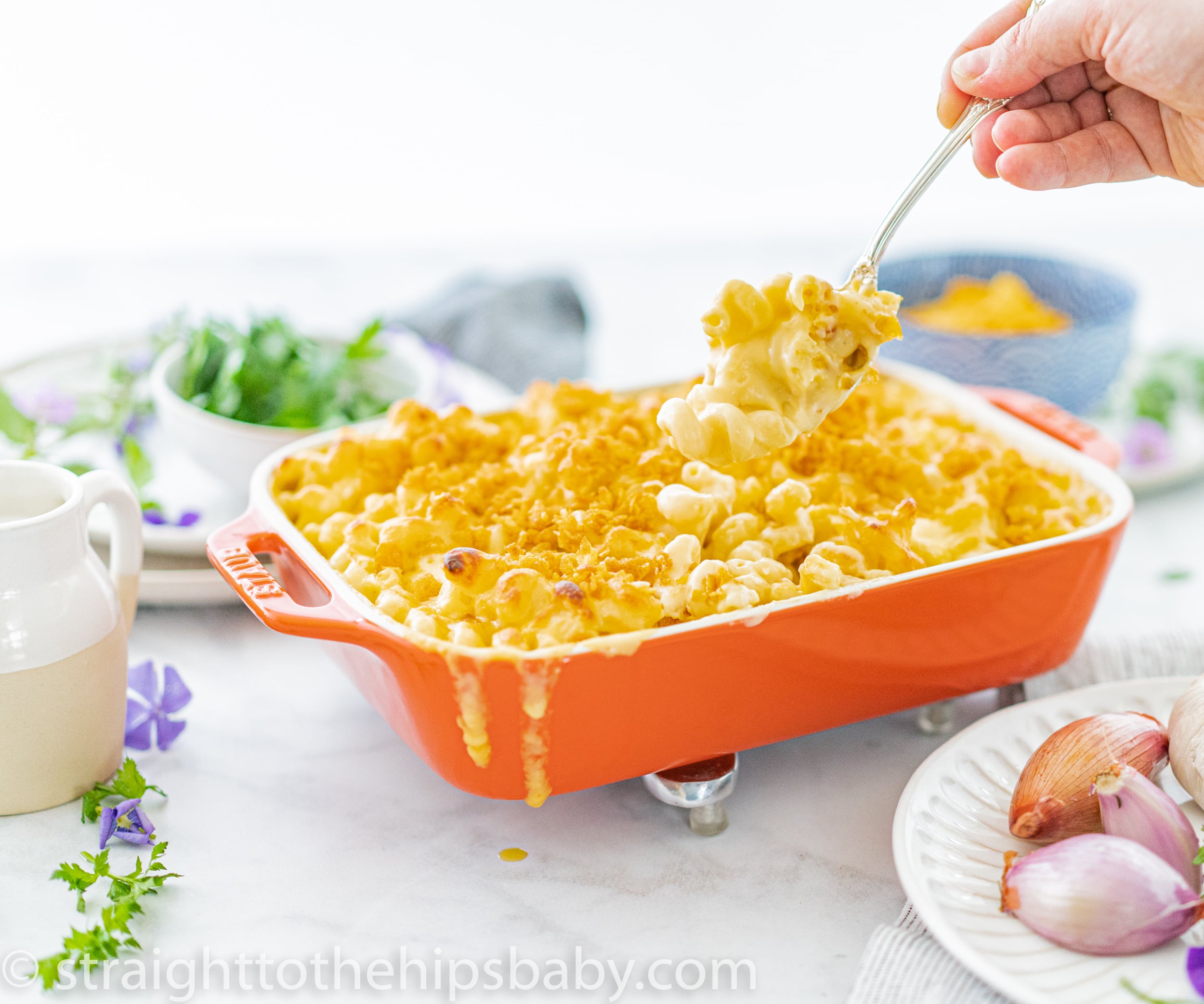 Creamy cheddar and Gruyère macaroni and cheese in a white baking dish with golden cornflake topping