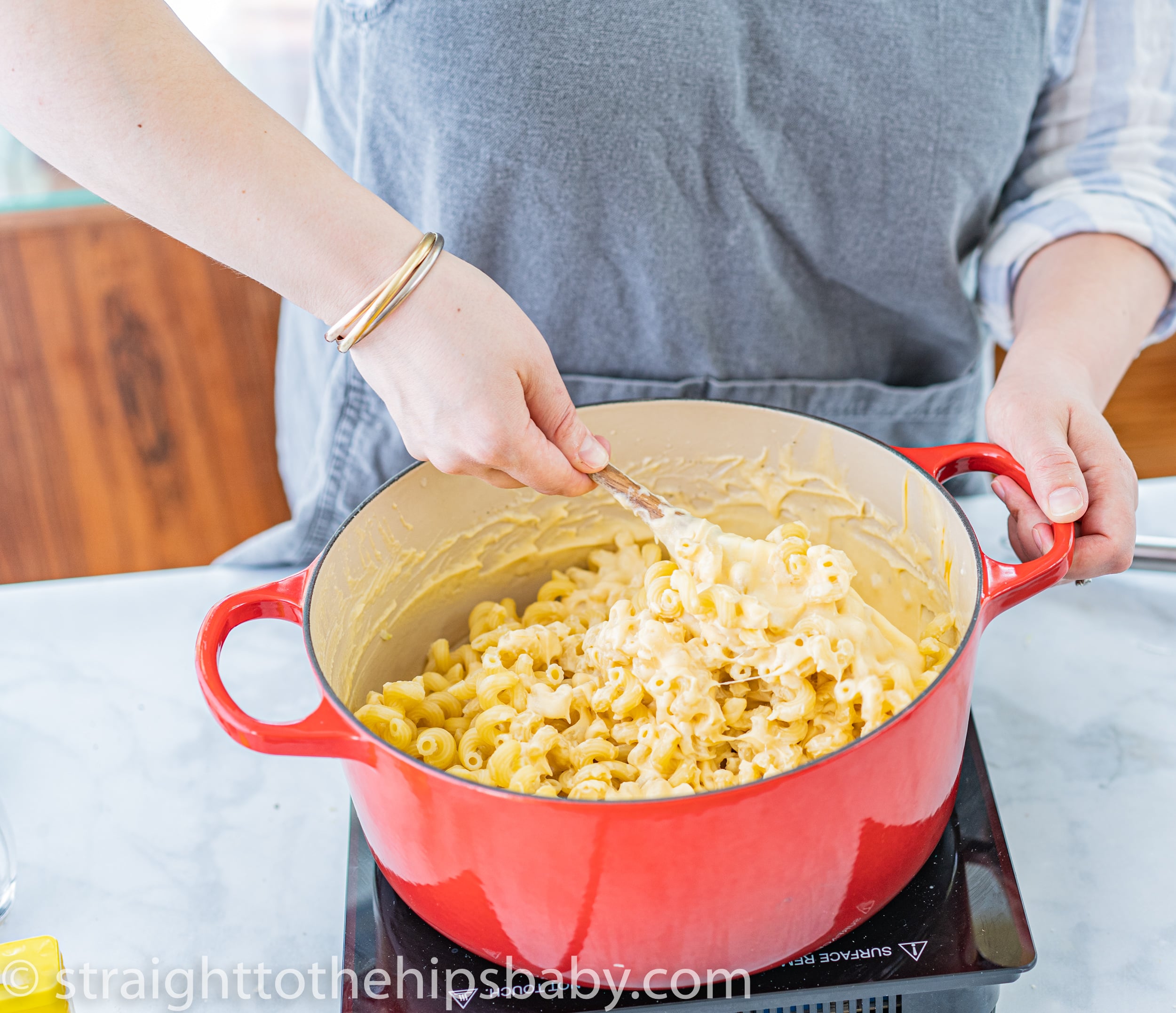 Cellentani spiral pasta being folded into a smooth cheddar Gruyère cheese sauce